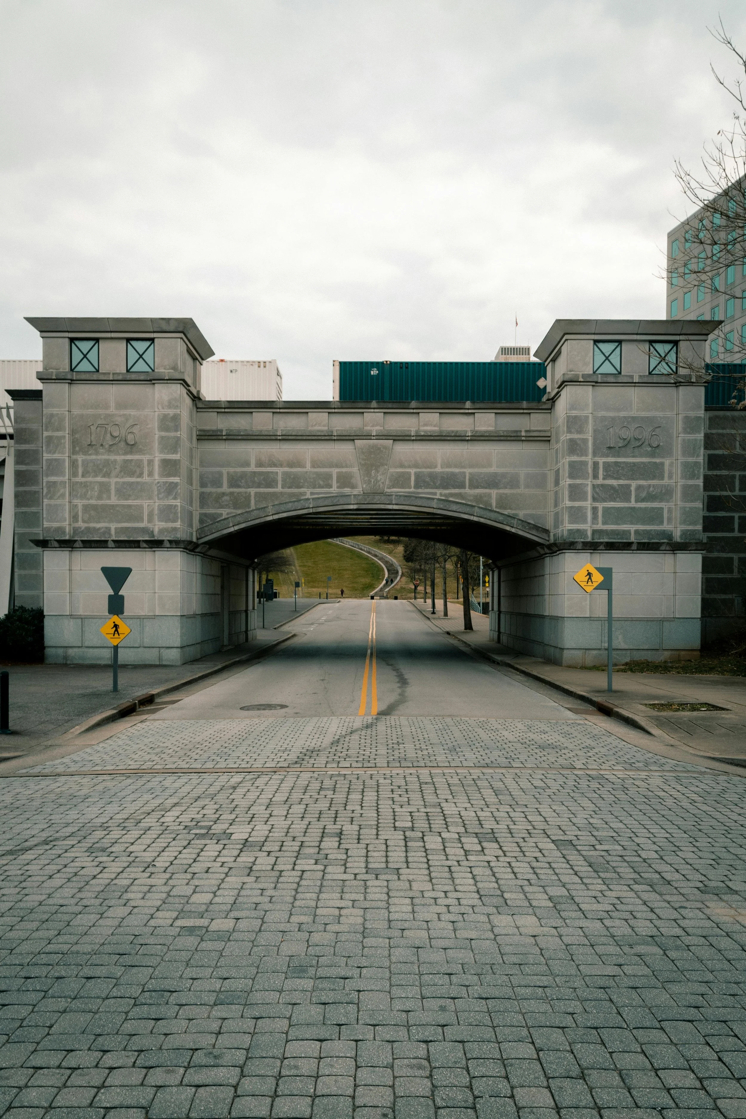 A stone underpass with the years 1796 and 1996 inscribed on its sides, and street crossing signs on both sides of the entrance.