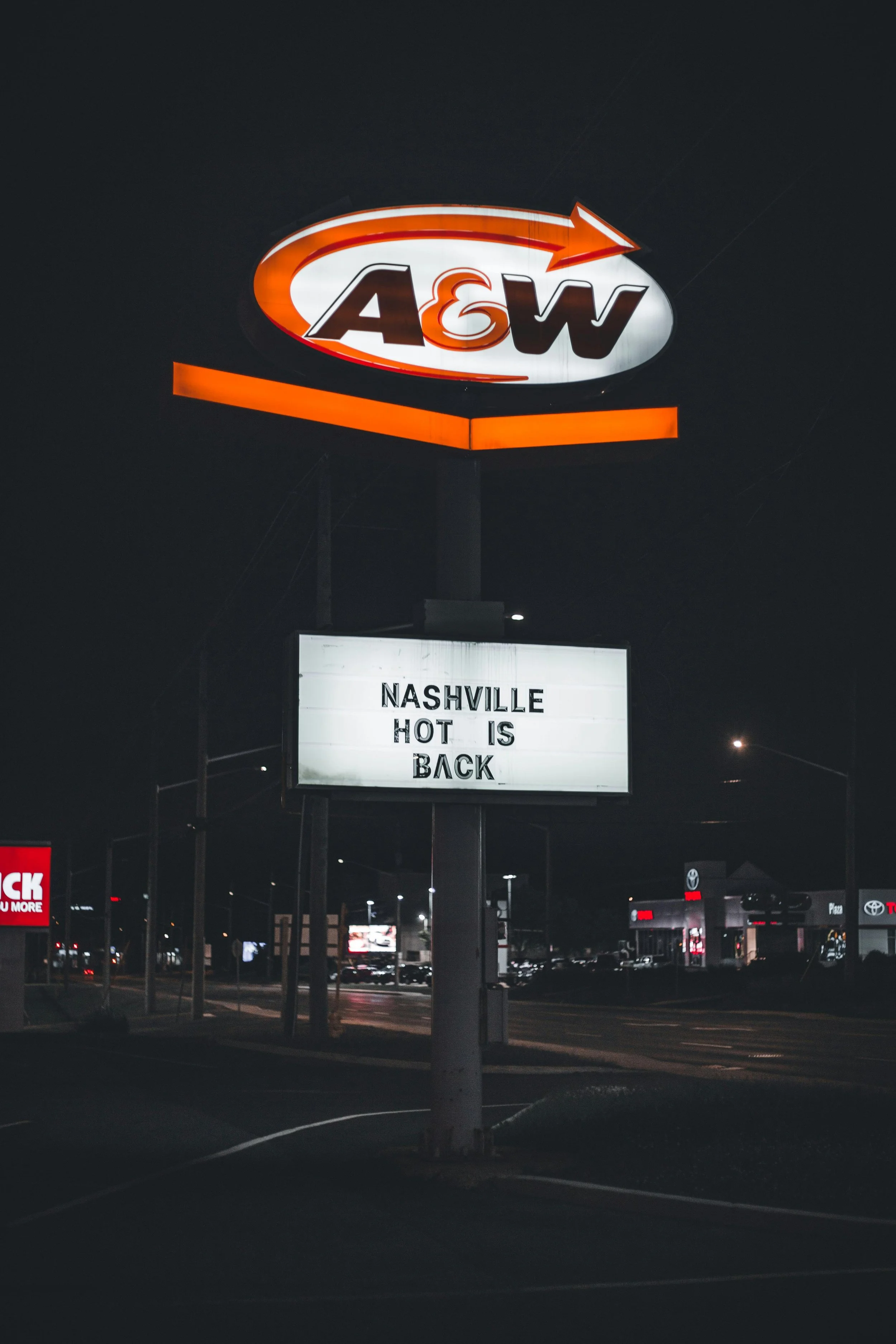 Nighttime sign with the A&W logo and a message board that says "Nashville hot is back."