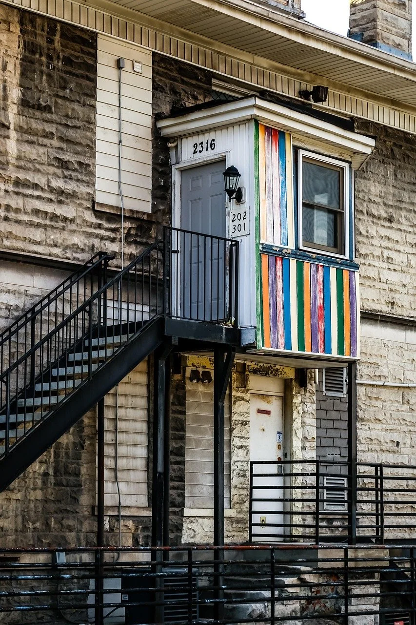 Apartment building with door, colorful wooden panels, and external staircase.