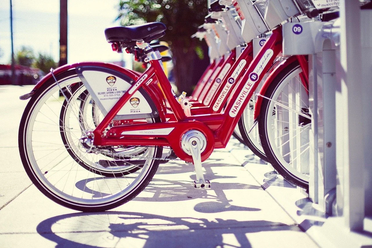 Red city bikes are parked at a bike-sharing station, with the words "Nashville B" visible on the bikes.