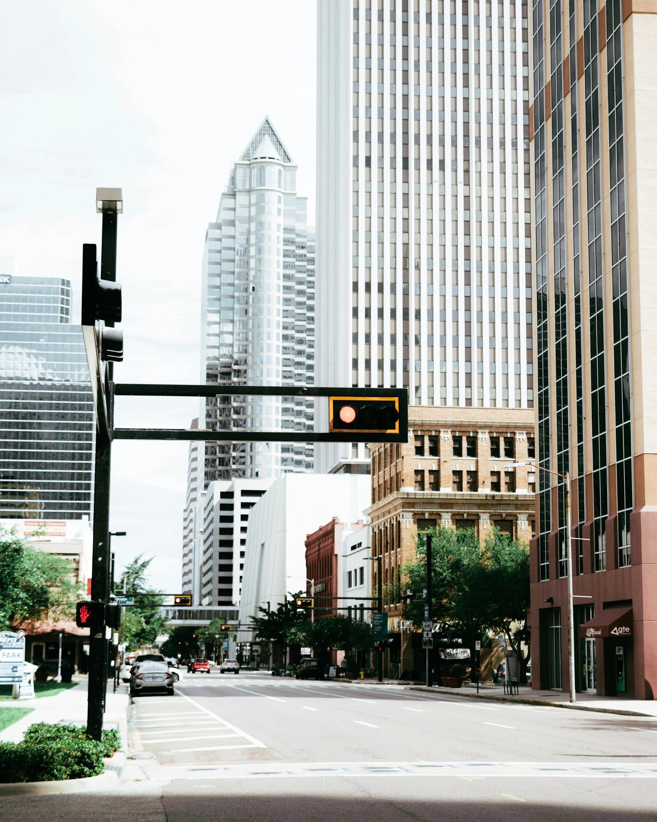 Urban street scene with tall skyscrapers, traffic lights, and cars on the road.