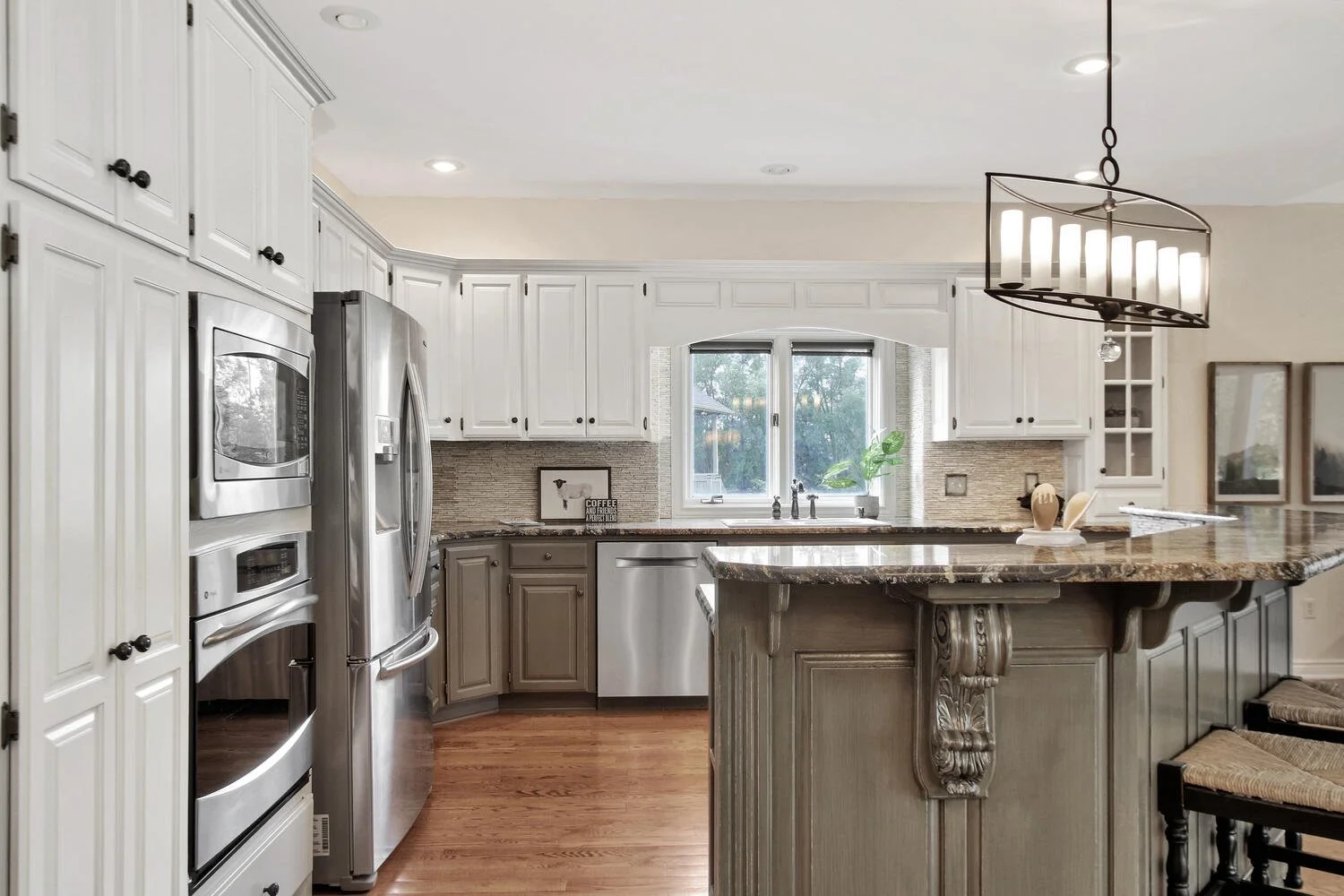 Modern kitchen with white cabinets, stainless steel appliances, granite countertops, and a decorative chandelier.