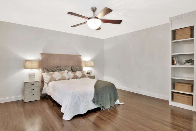 Bedroom with a bed, nightstands, lamps, ceiling fan, and a built-in shelf