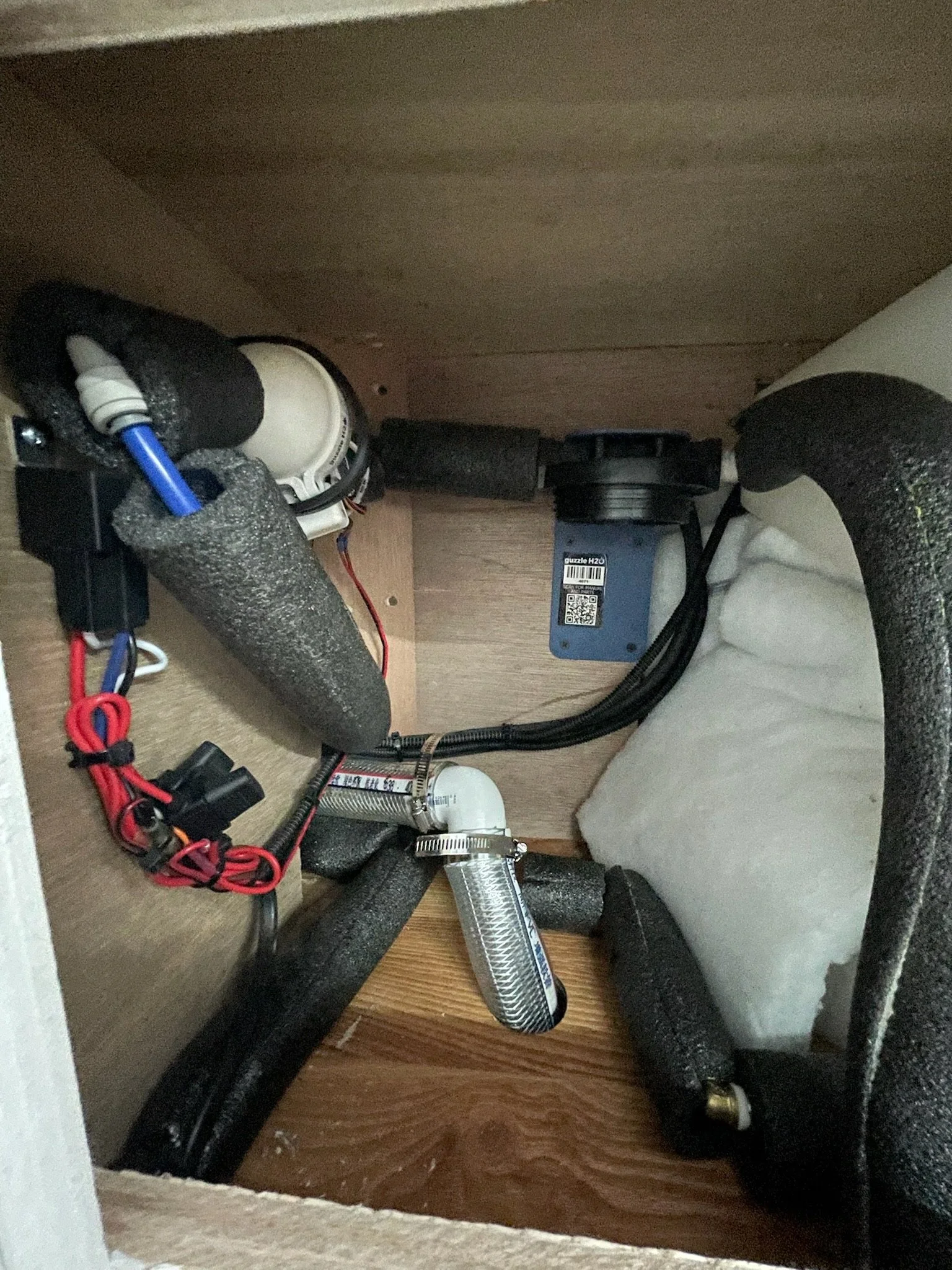 Interior of a cabinet containing plumbing components and insulation