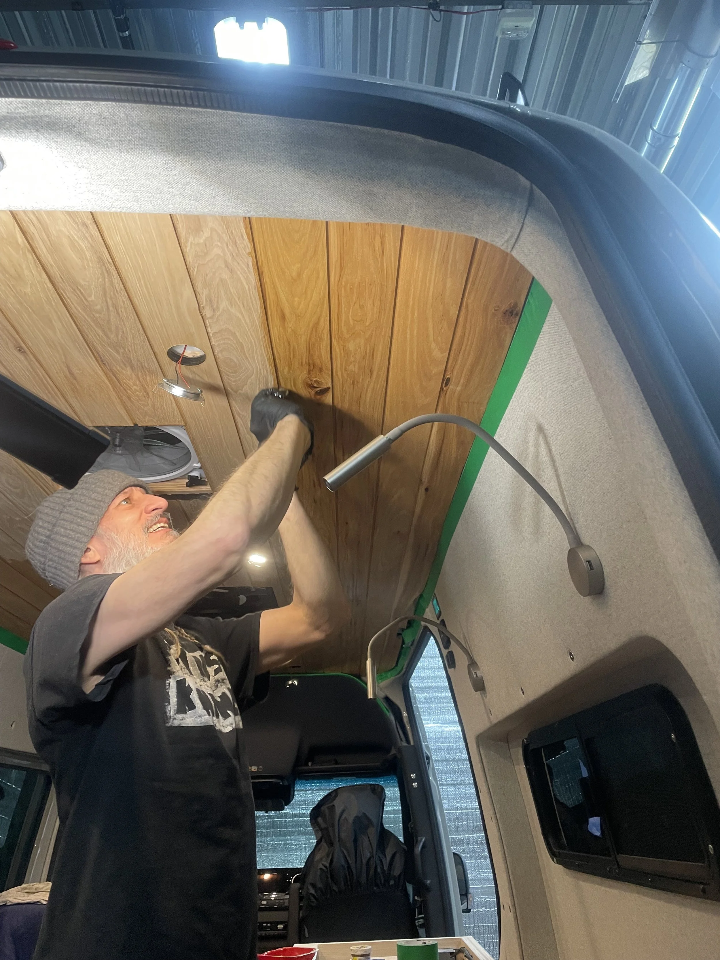 Person installing a wooden ceiling in a van interior.