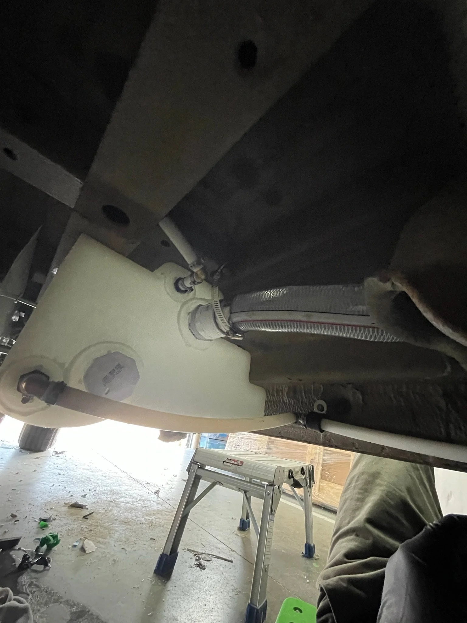 Underside of a vehicle showing piping and a step stool