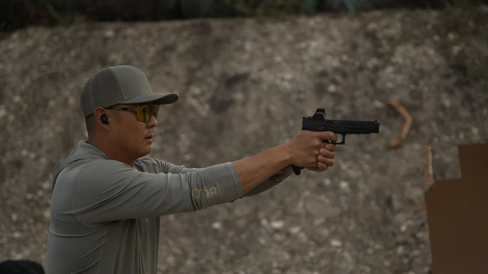 A shooter aiming a handgun with both hands at Rooftop Shooting Range