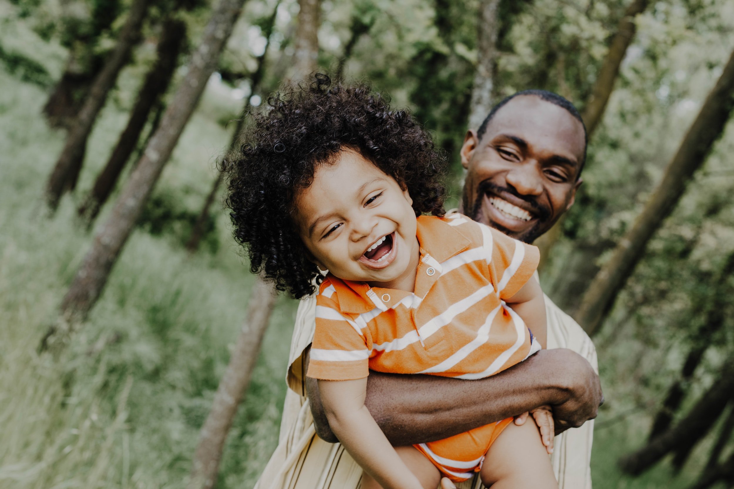 father picking up son and laughing in the woods