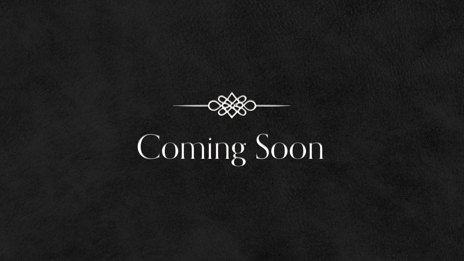 A black textured background with a decorative white emblem above the words "Coming Soon" in white font.