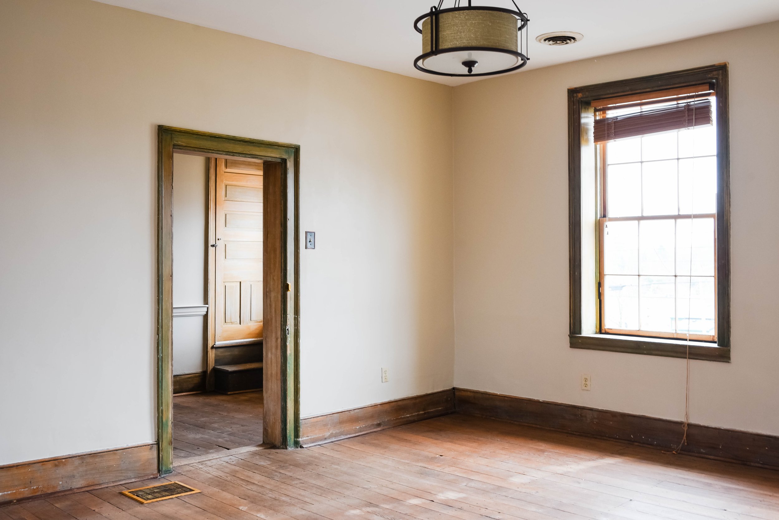 Empty room with wooden floor, window, and doorway