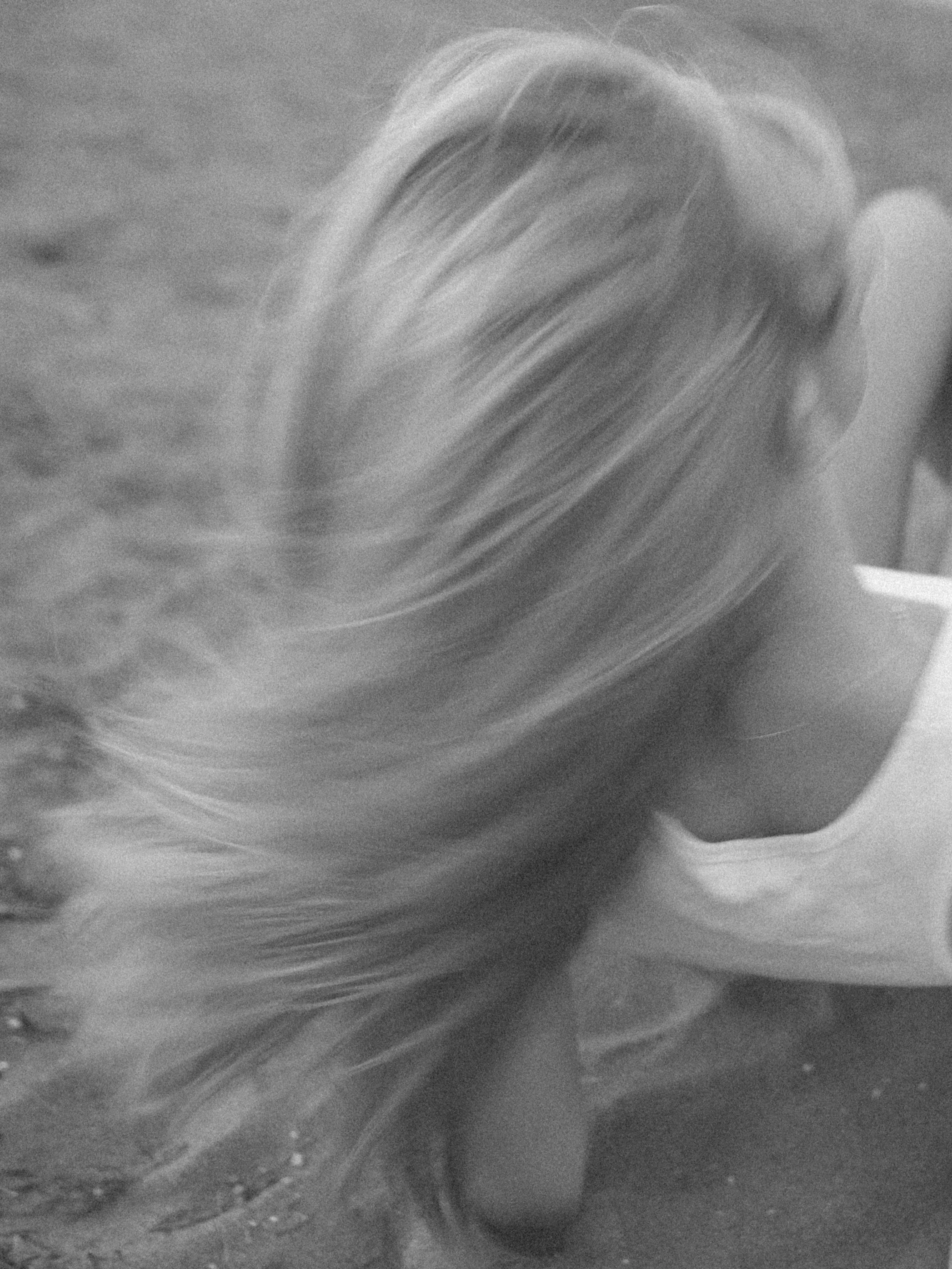 A woman with long blonde hair and a face mask leaning over a surface, possibly washing her hands.