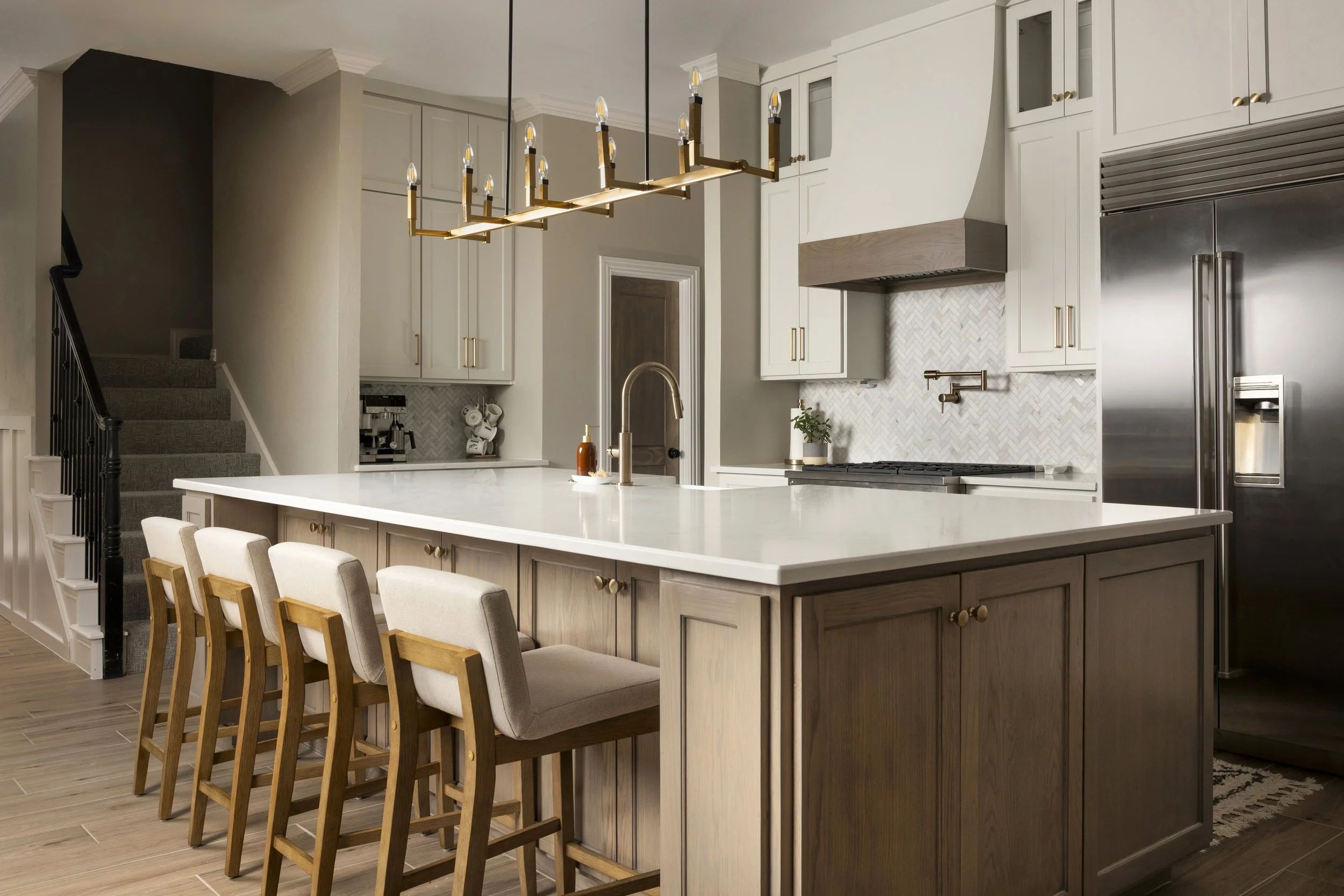 Modern kitchen with white cabinets, marble countertop, black pendant lights, black faucet, and a white vase with green plants.