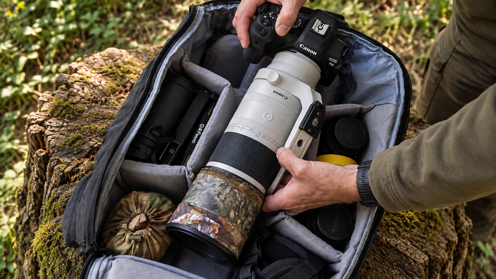 Mans hands removing a Canon RF200-800mm lens and Canon R6 camera from A K&F Concept 30L camera backpack in the field.
