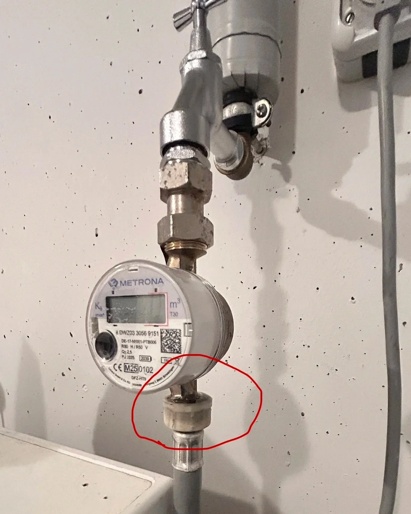 Wasserzähler an einer Wasserleitung, mit einem Rohrstück, das durch eine rote Markierung hervorgehoben ist.