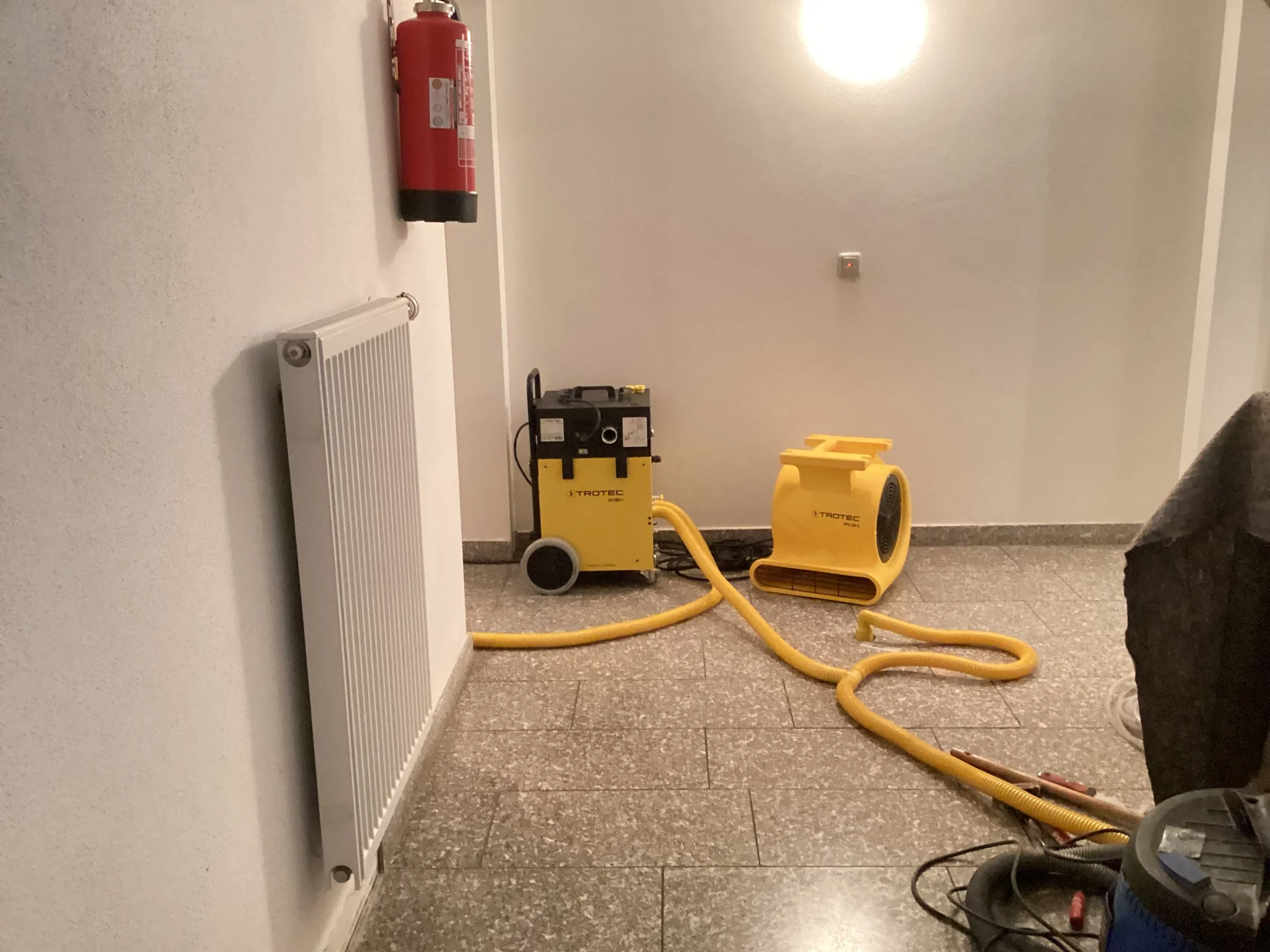 Professionelle Dämmschichttrocknung im Eingangsbereich mit Trotec Qube+ und Ventilator in Kolbermoor