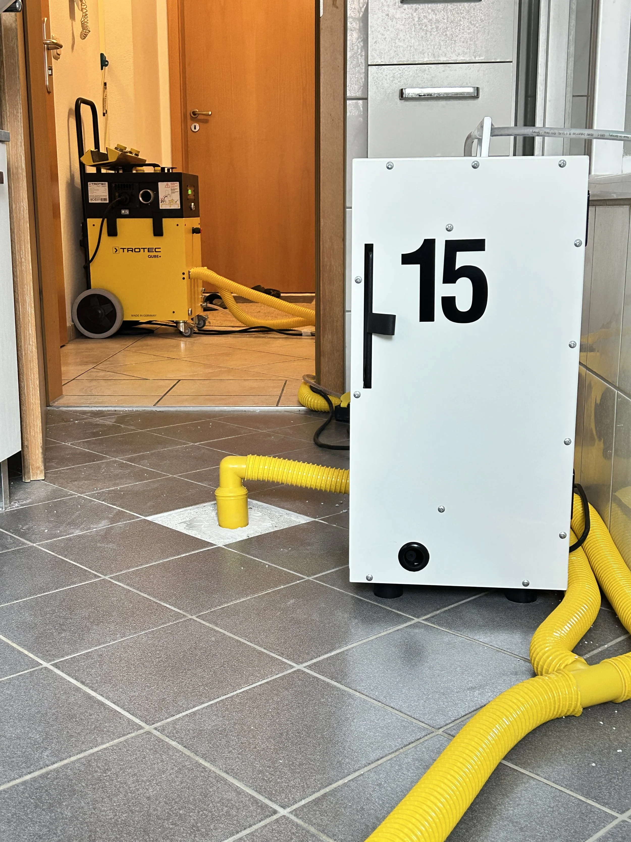 Professionelle Raumtrocknung in Neubeuern mit Trotec Qube und Seitenkanalverdichter zur effizienten Trocknung der Dämmschicht nach einem Wasserschaden.