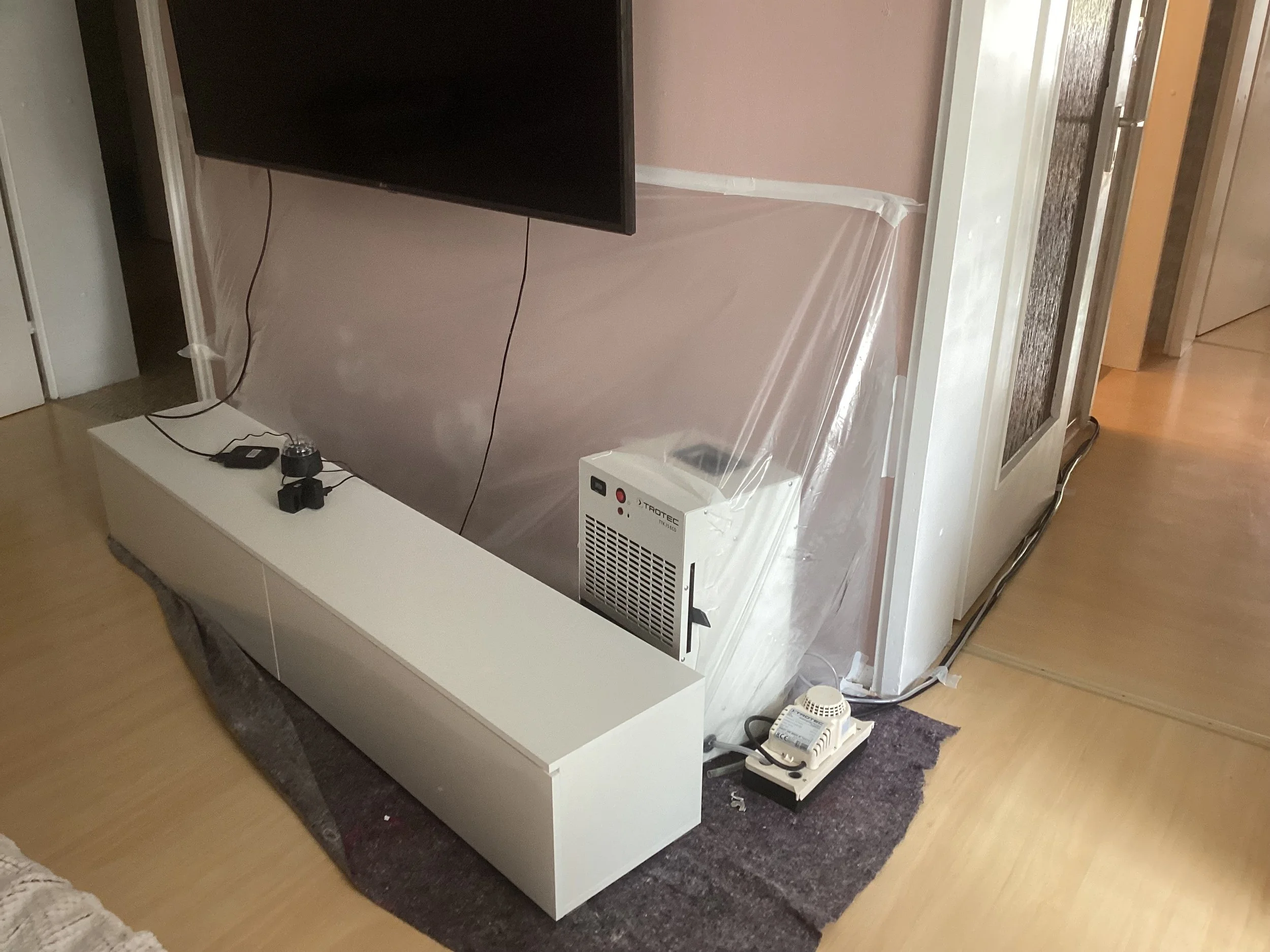 Professionelle Wandtrocknung nach Wasserschaden im Wohnzimmer mit modernen Trocknungsgeräten