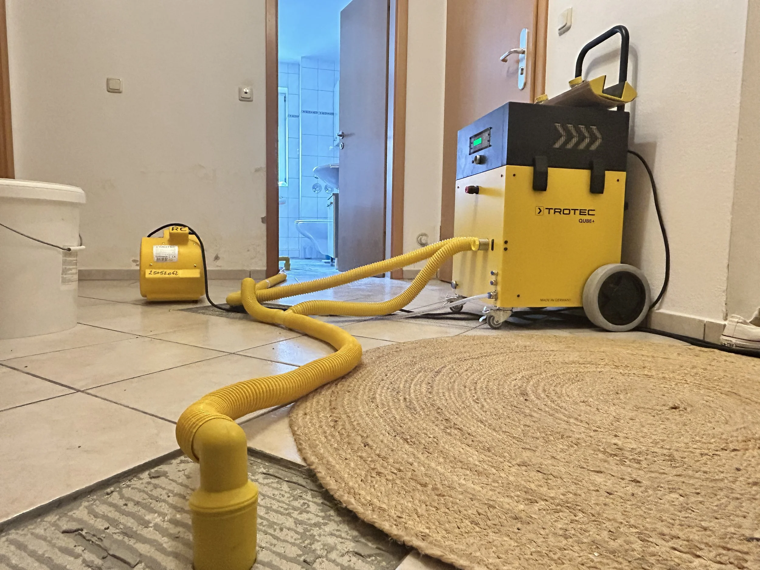 Professionelle Dämmschichttrocknung in Neubeuern nach Wasserschaden mit Trotec Qube und Seitenkanalverdichter zur Trocknung der Dämmschicht unter dem Estrich