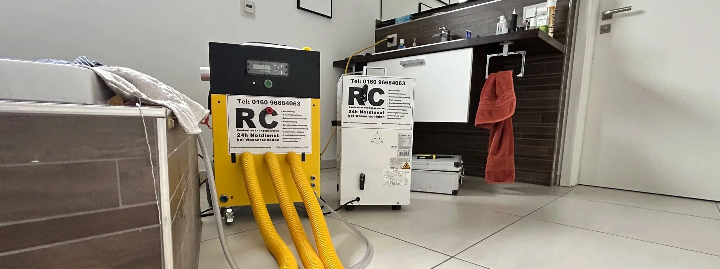 Ein Raum mit Wasser-Notdienstgeräten und Reinigungsutensilien, darunter ein gelber Wasserabsorptionsmaschine, eine weiße Box mit Datenetikett, ein rotes Handtuch, ein Schrank, eine Arbeitskiste und ein Kabel auf der Küchenarbeitsplatte.