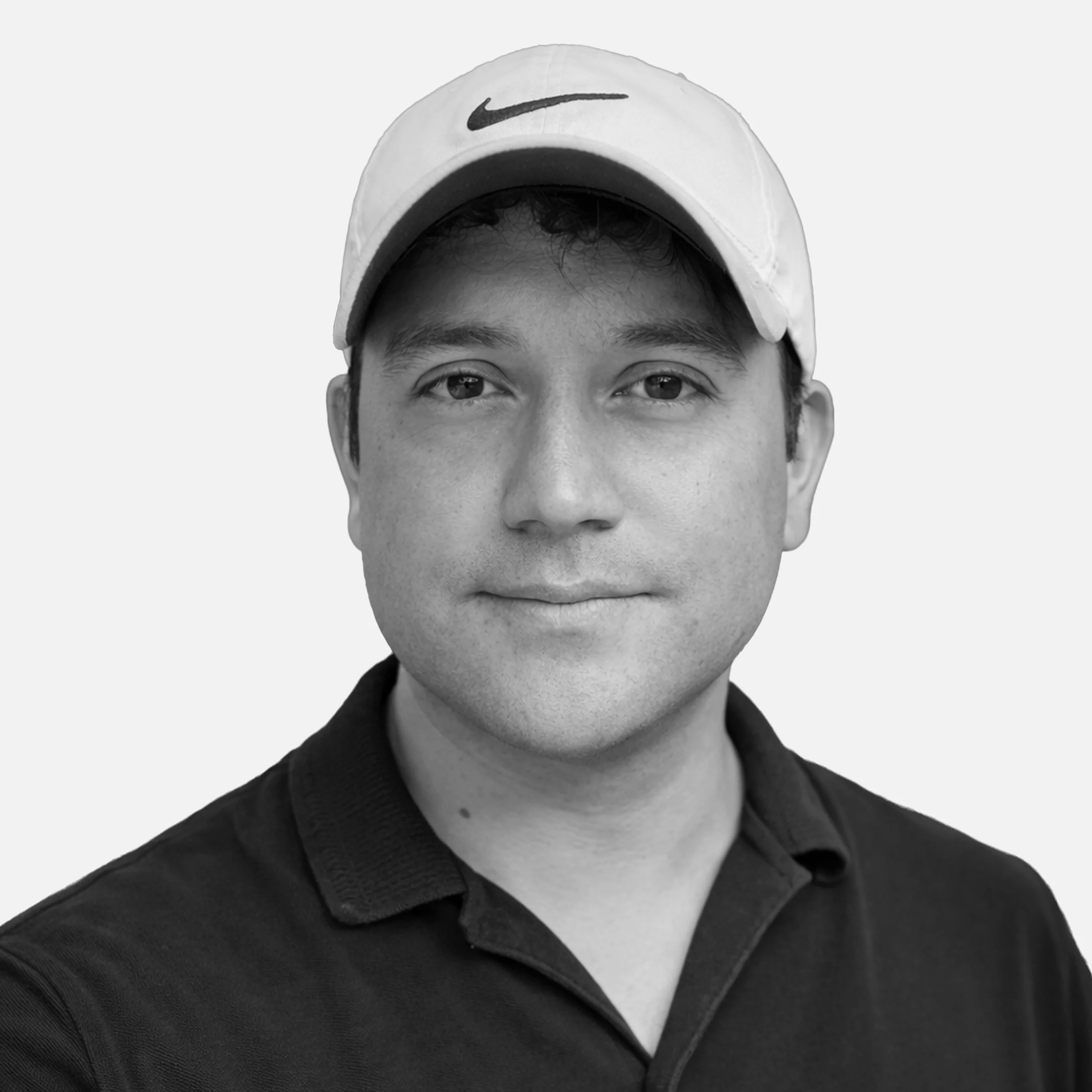 A black-and-white portrait of a man wearing a white baseball cap with a Nike logo and a black collared shirt.