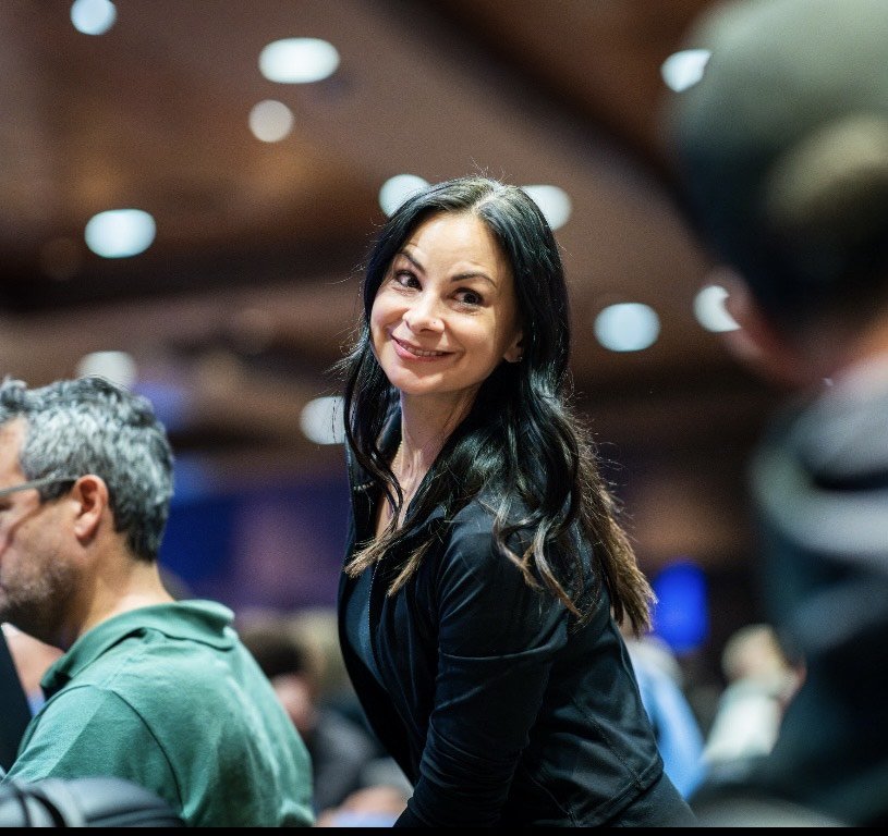 Smiling woman with dark hair massaging a poker player during the World Series of Poker event at Harrah's Pompano Beach