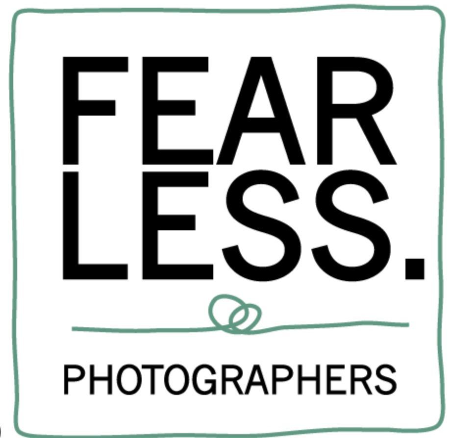 A sign that reads "Fear Less. Photographers" with a simple green border and a small green looped line underneath the text.