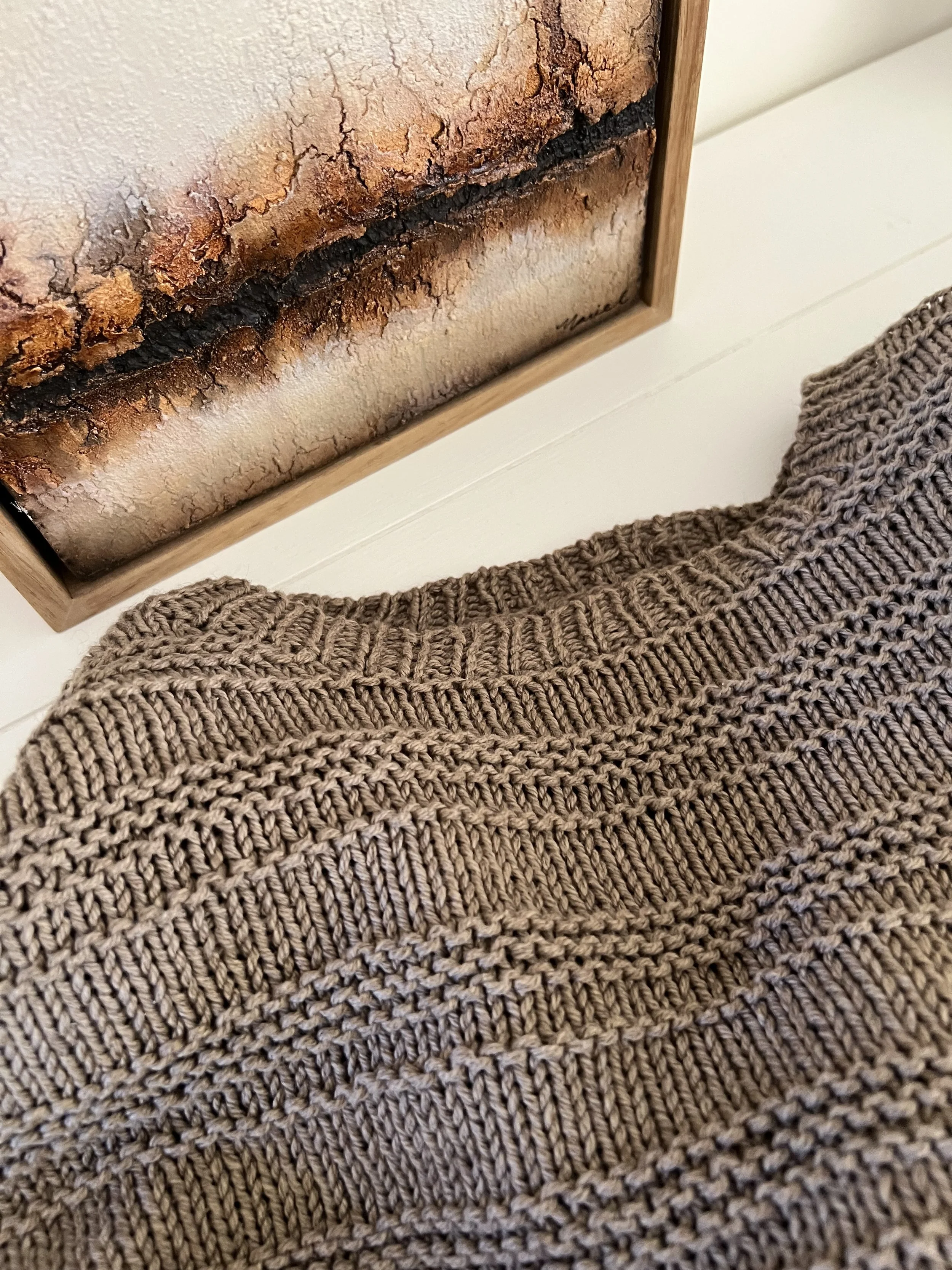 Marie Larkin textured painting and knitted garment in warm tones of brown.