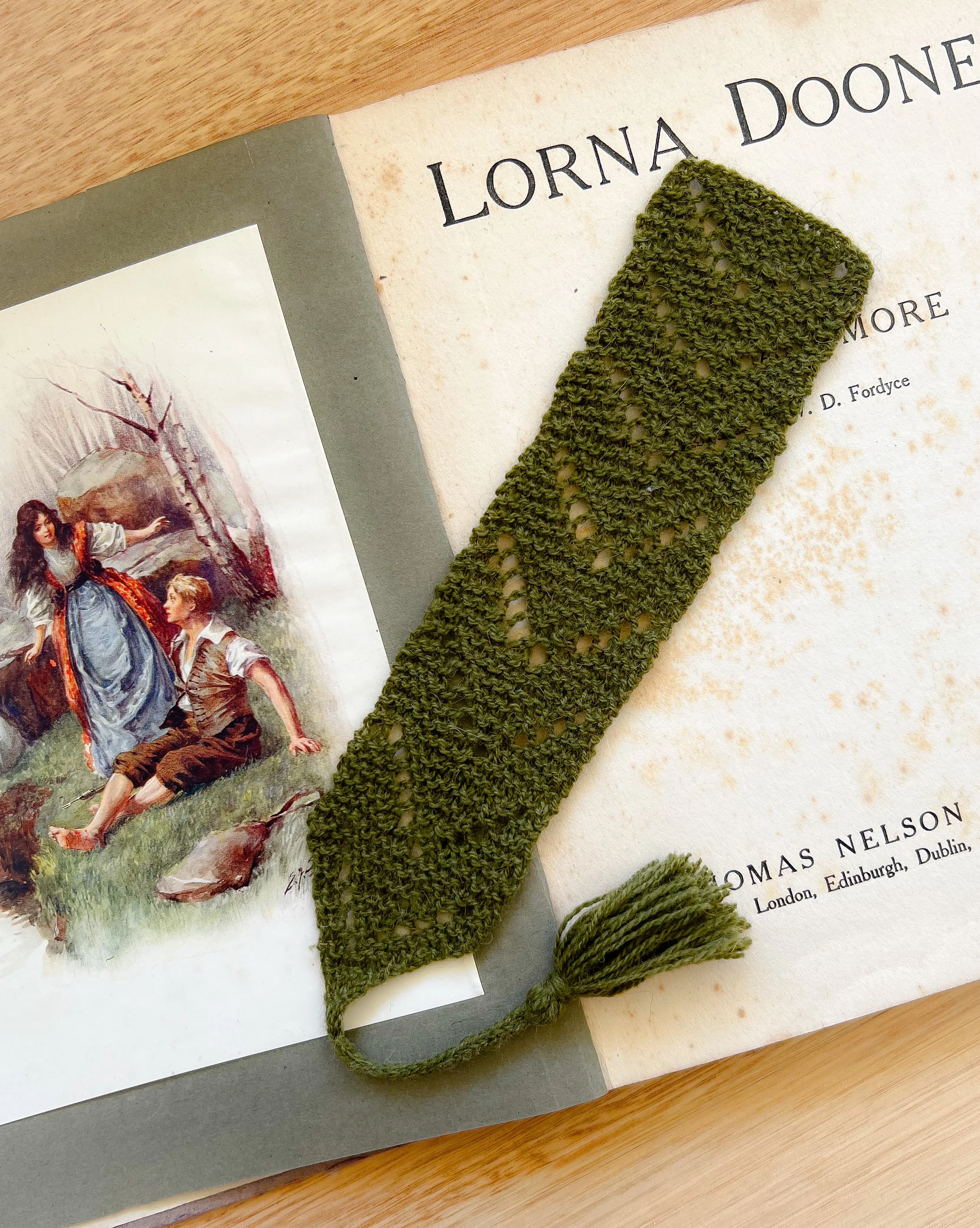 A green lace pattern hand knit book mark in an antique book.