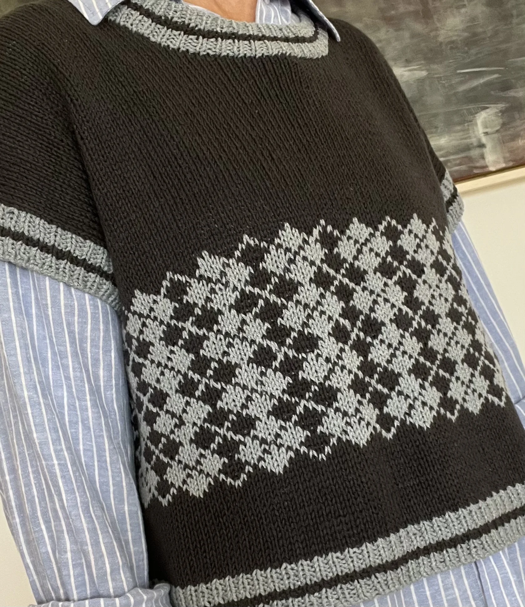 Black and blue colour work vest worn by a woman over a blue and white striped shirt.