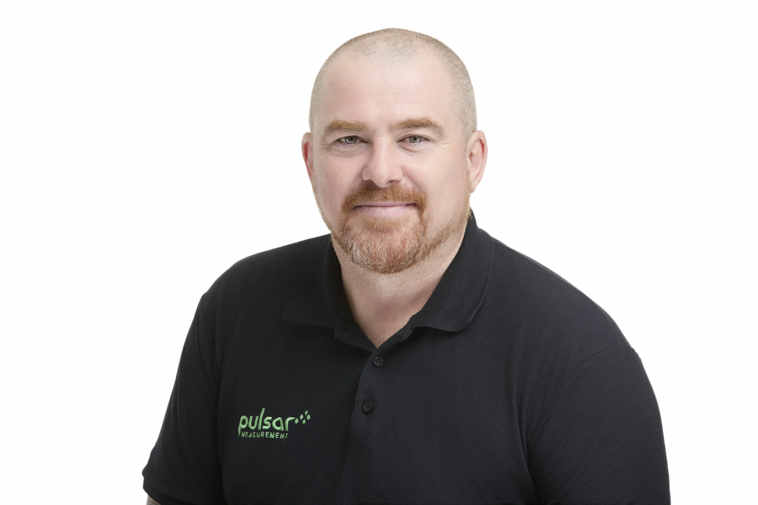Headshot of a bald man with a beard, wearing a black polo shirt with a green logo that reads 'pulsar THE MEASUREMENT' against a white background.