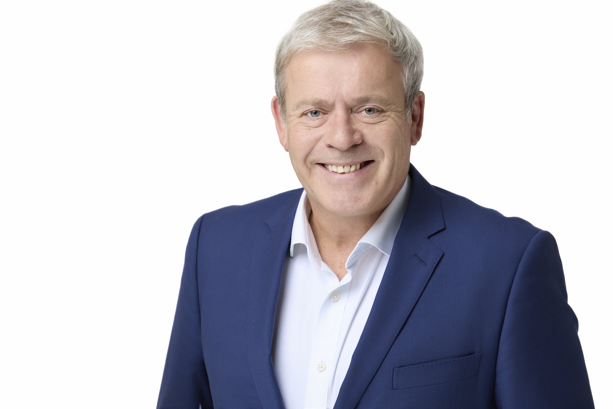 A smiling middle-aged man with gray hair wearing a dark blue suit jacket and white shirt against a plain white background.