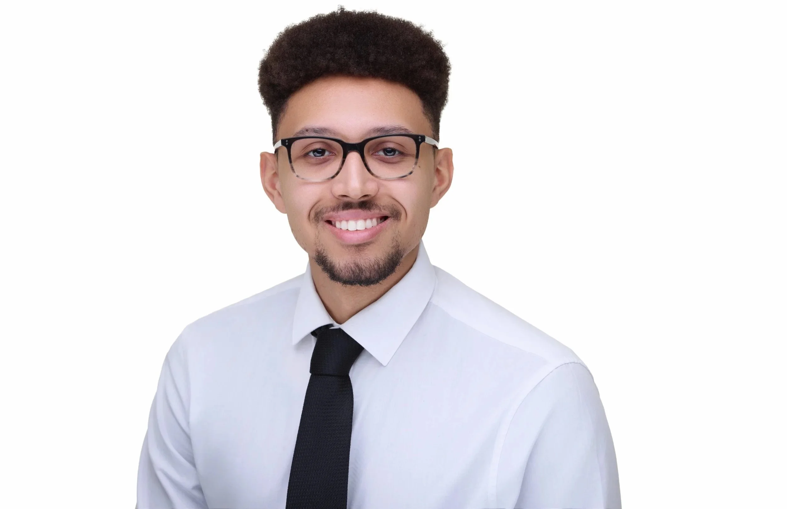 Portrait of a young man with glasses, short curly hair, a goatee, wearing a white shirt and black tie, smiling against a plain white background.