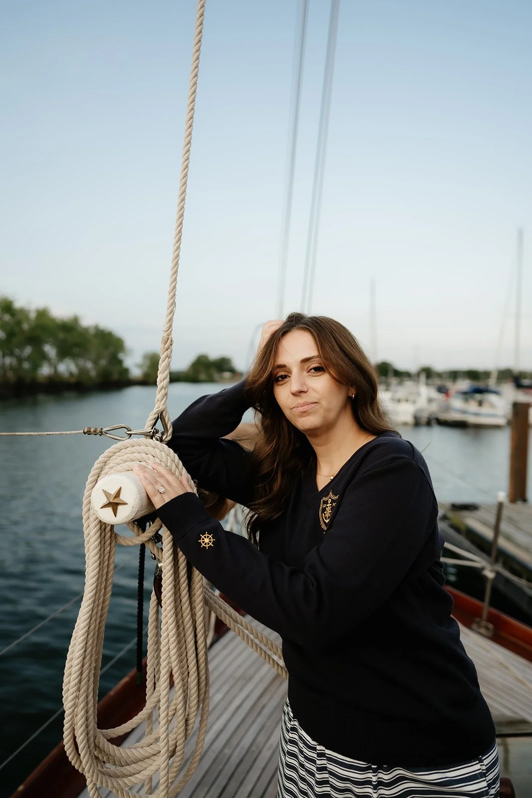 Navy women’s V-neck yacht club sweater with gold anchor crest and nautical helm details, a classic preppy coastal sweater.
