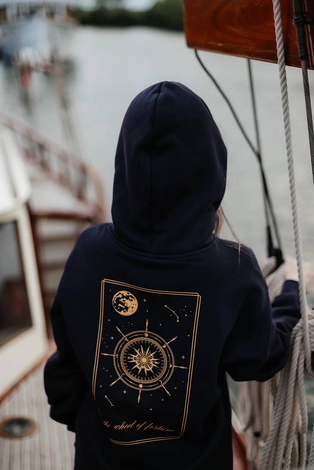 Navy witchy graphic hoodie for fall and Halloween featuring a celestial wheel of fortune design with gold moon, stars, constellations and compass details.