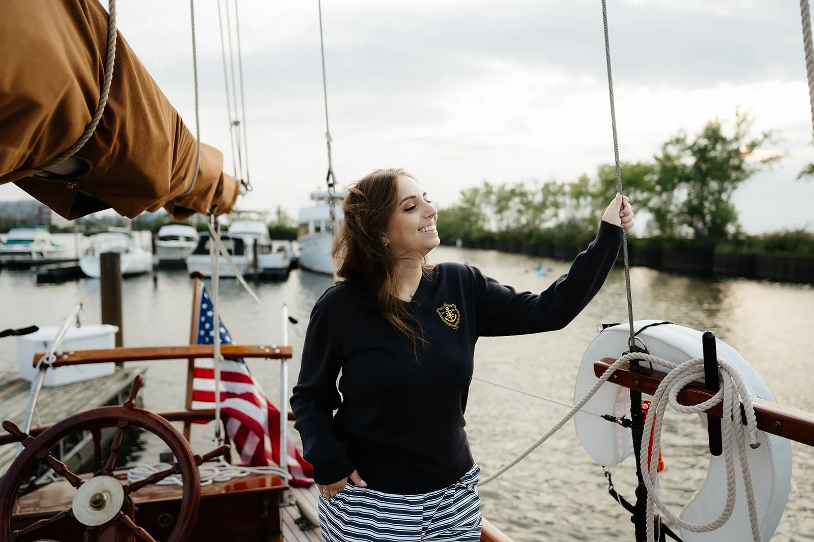 Navy women’s V-neck yacht club sweater with gold anchor crest and nautical helm details, a classic preppy coastal sweater.