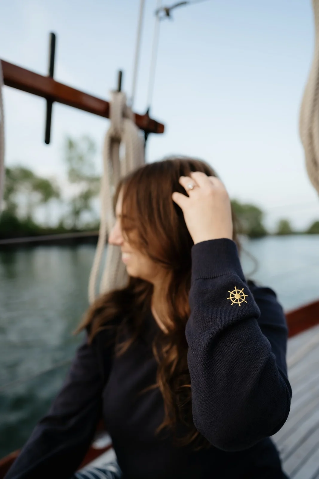 Navy women’s V-neck yacht club sweater with gold anchor crest and nautical helm details, a classic preppy coastal sweater.