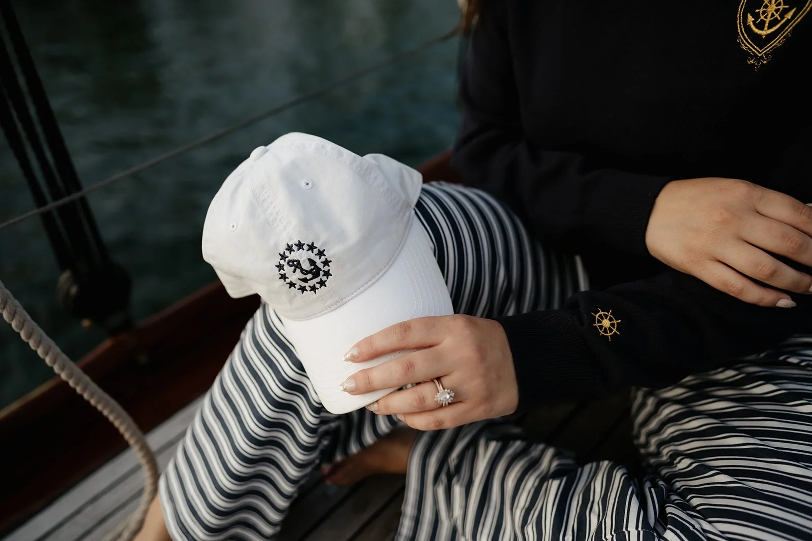 Navy women’s V-neck yacht club sweater with gold anchor crest and nautical helm details, a classic preppy coastal sweater.