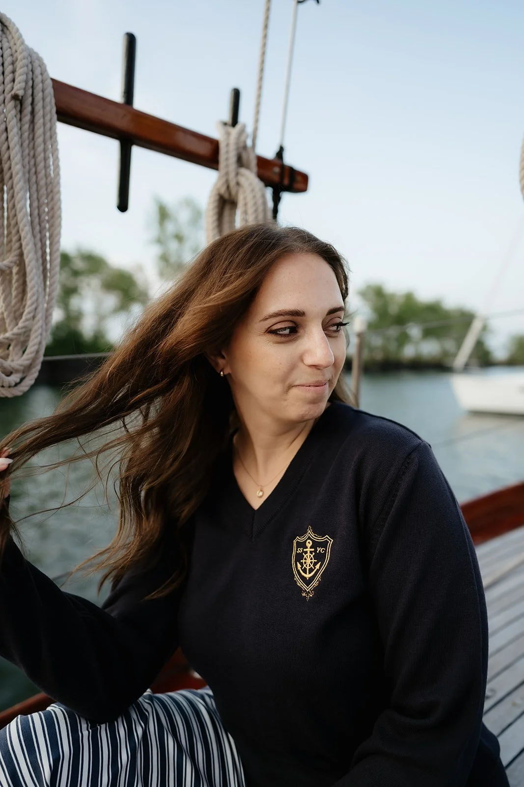Navy women’s V-neck yacht club sweater with gold anchor crest and nautical helm details, a classic preppy coastal sweater.
