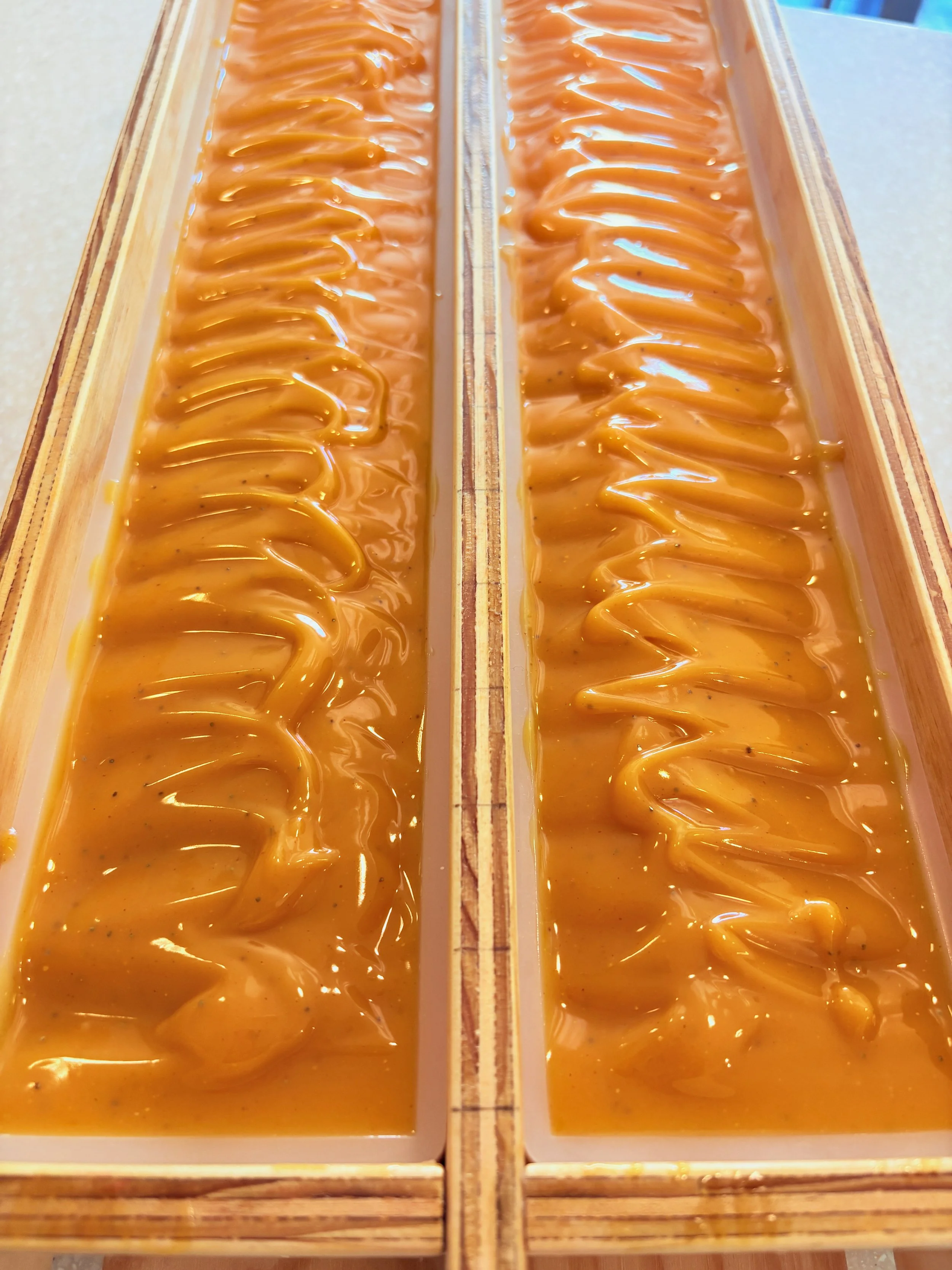 Two rectangular wooden display boxes filled with swirled caramel fudge, with a wooden stick placed vertically along the center dividing the two.