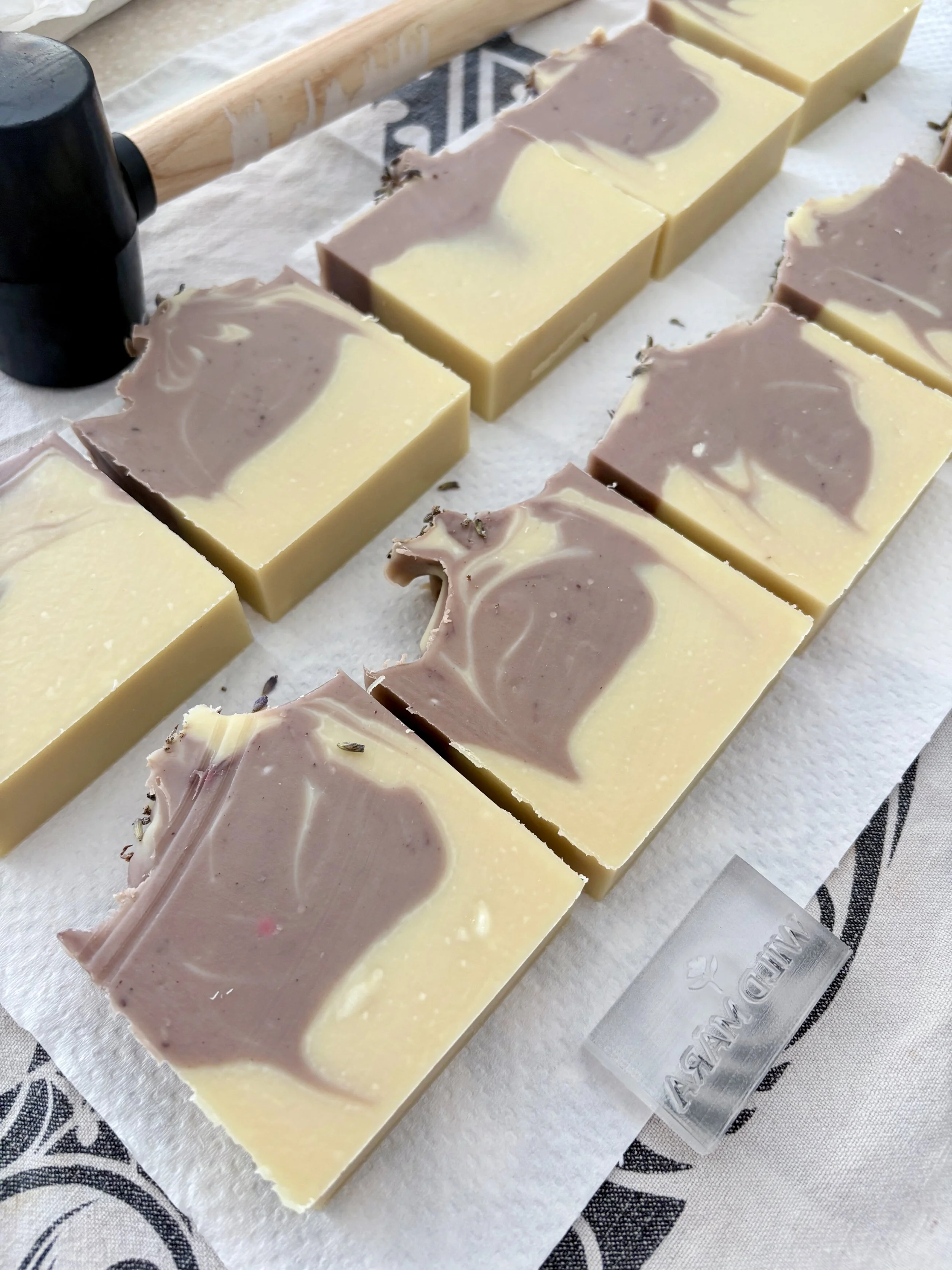 Slices of marble-patterned soap with swirls of beige and gray, arranged on a white surface with a textured cloth underneath.