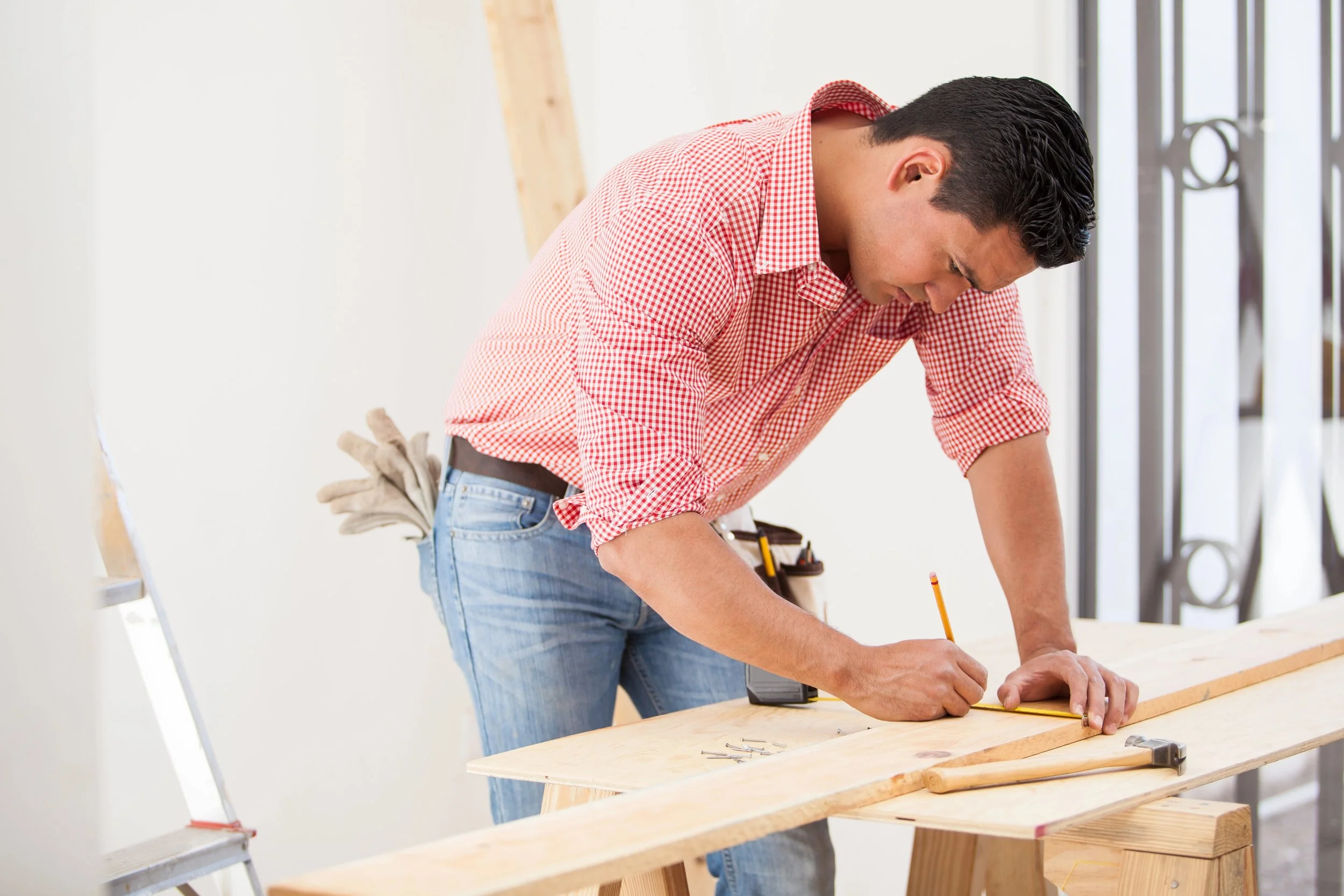 Contractor using a pencil to mark cut lines on wood