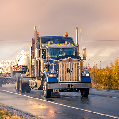 Semi truck with attached trailer driving down the highway.