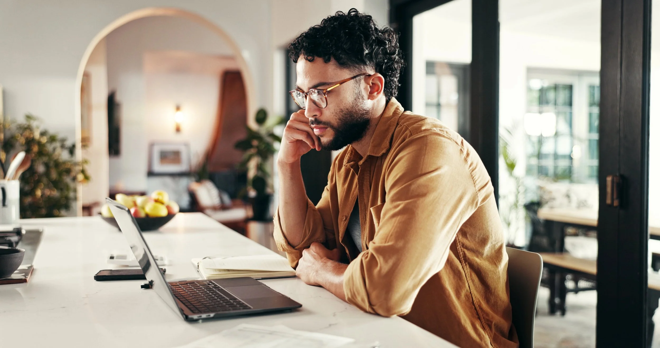 Hispanic/Latino freelancer sits in front of a computer in his home office