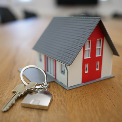 Miniature model of a home sitting on a table next to a key on a keychain.