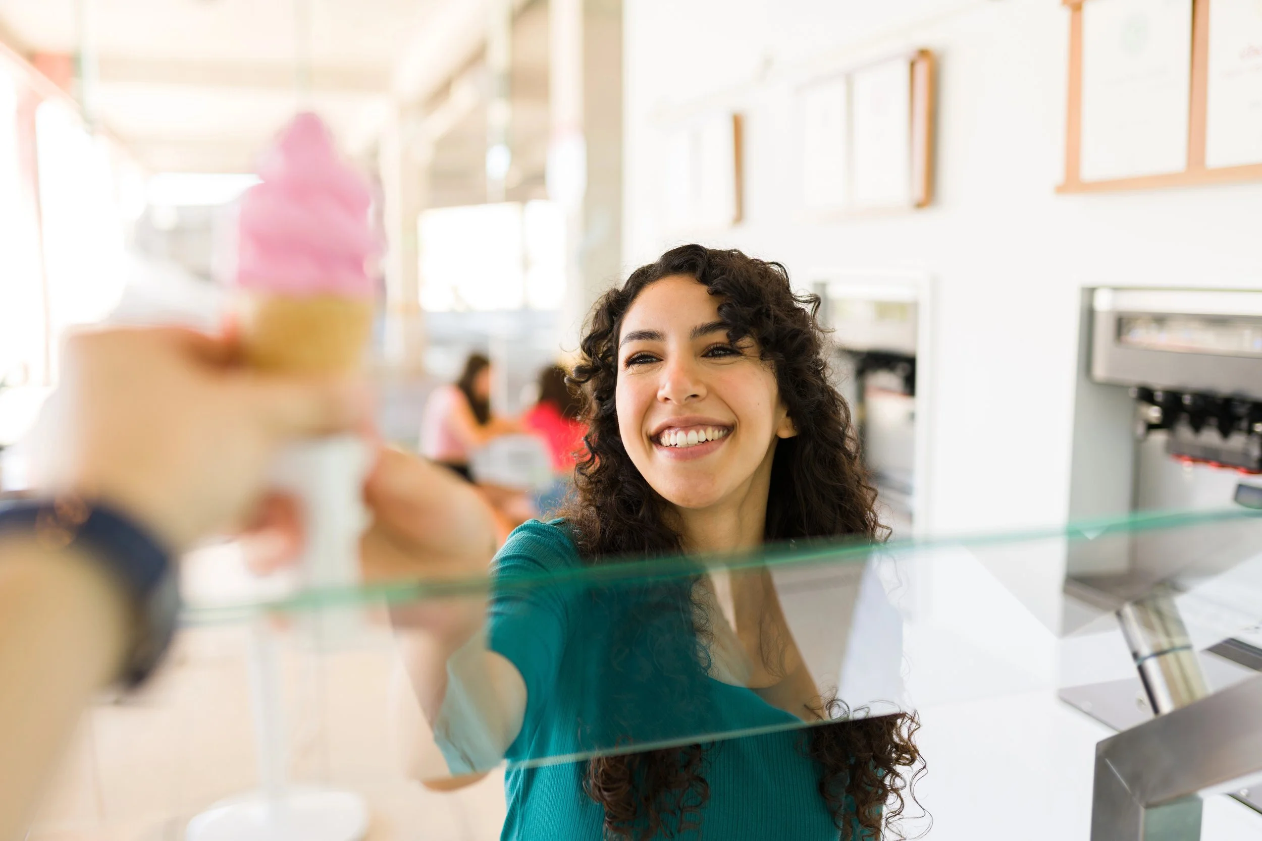 Female ice cream shop owner grabs ice cream cone from employee.