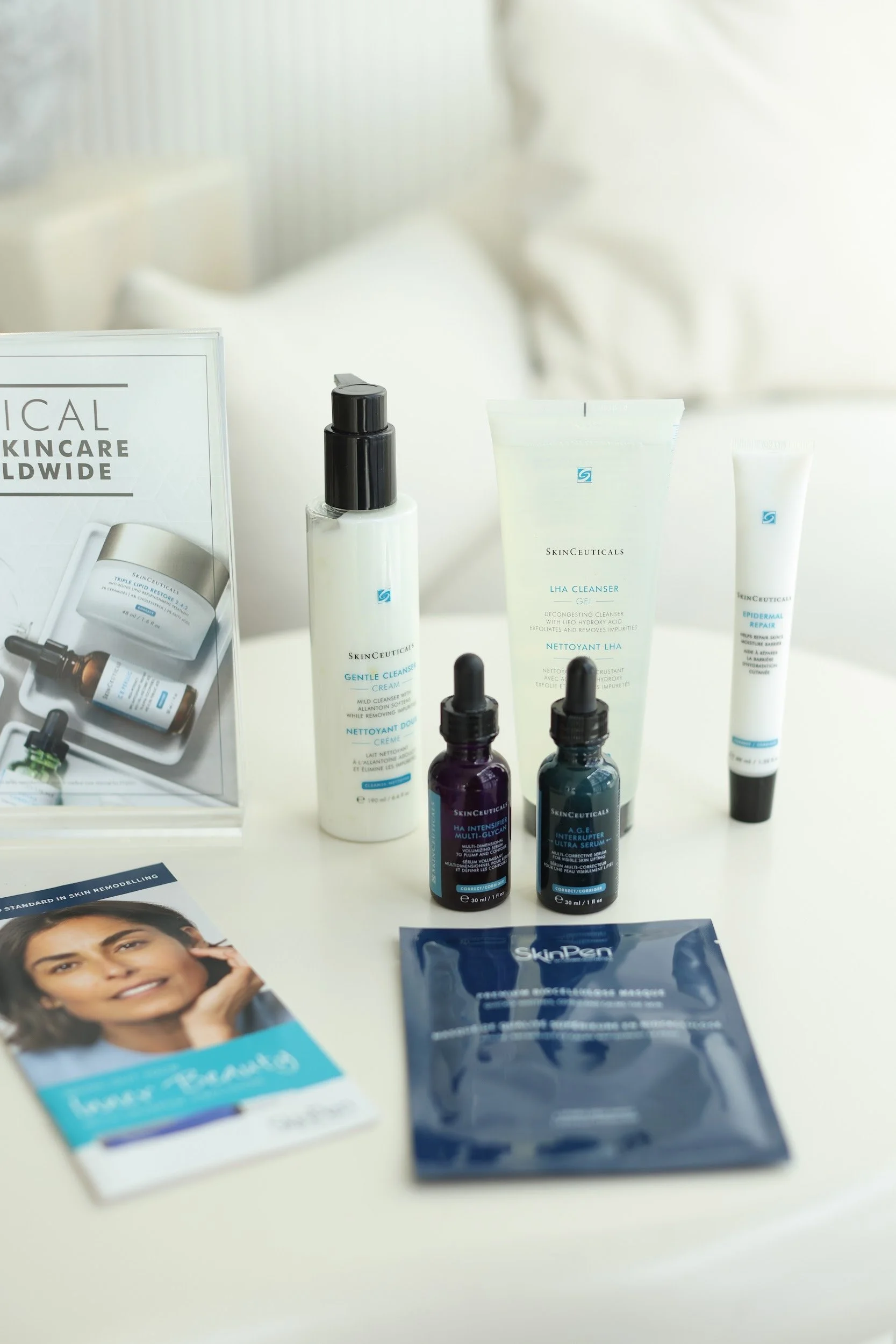 Skincare products and pamphlet on a white surface, including bottles, tubes, and a packet of SkinPen wipes.