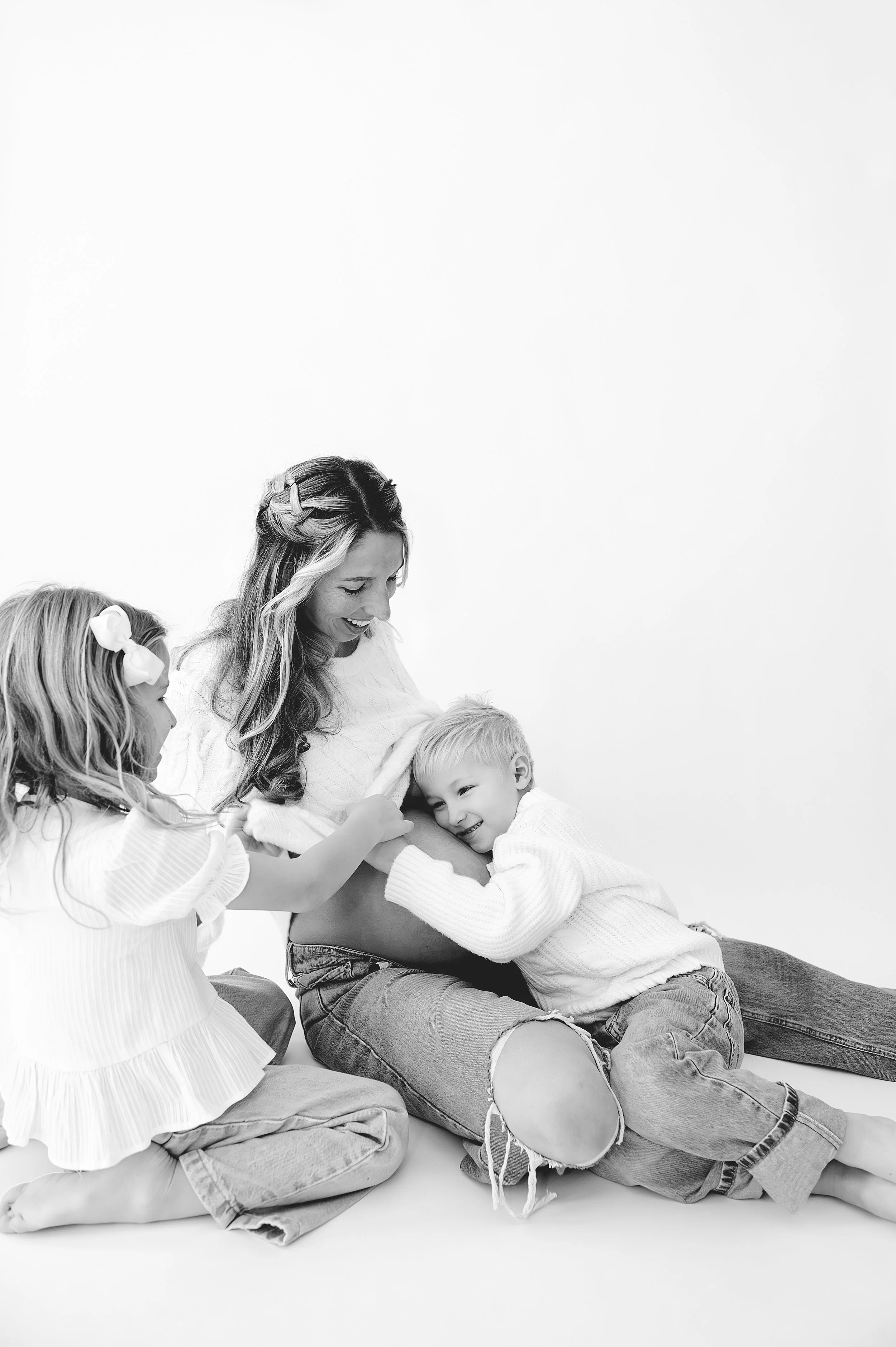 mom and kids maternity studio photo in black and white with jeans and belly hanging out