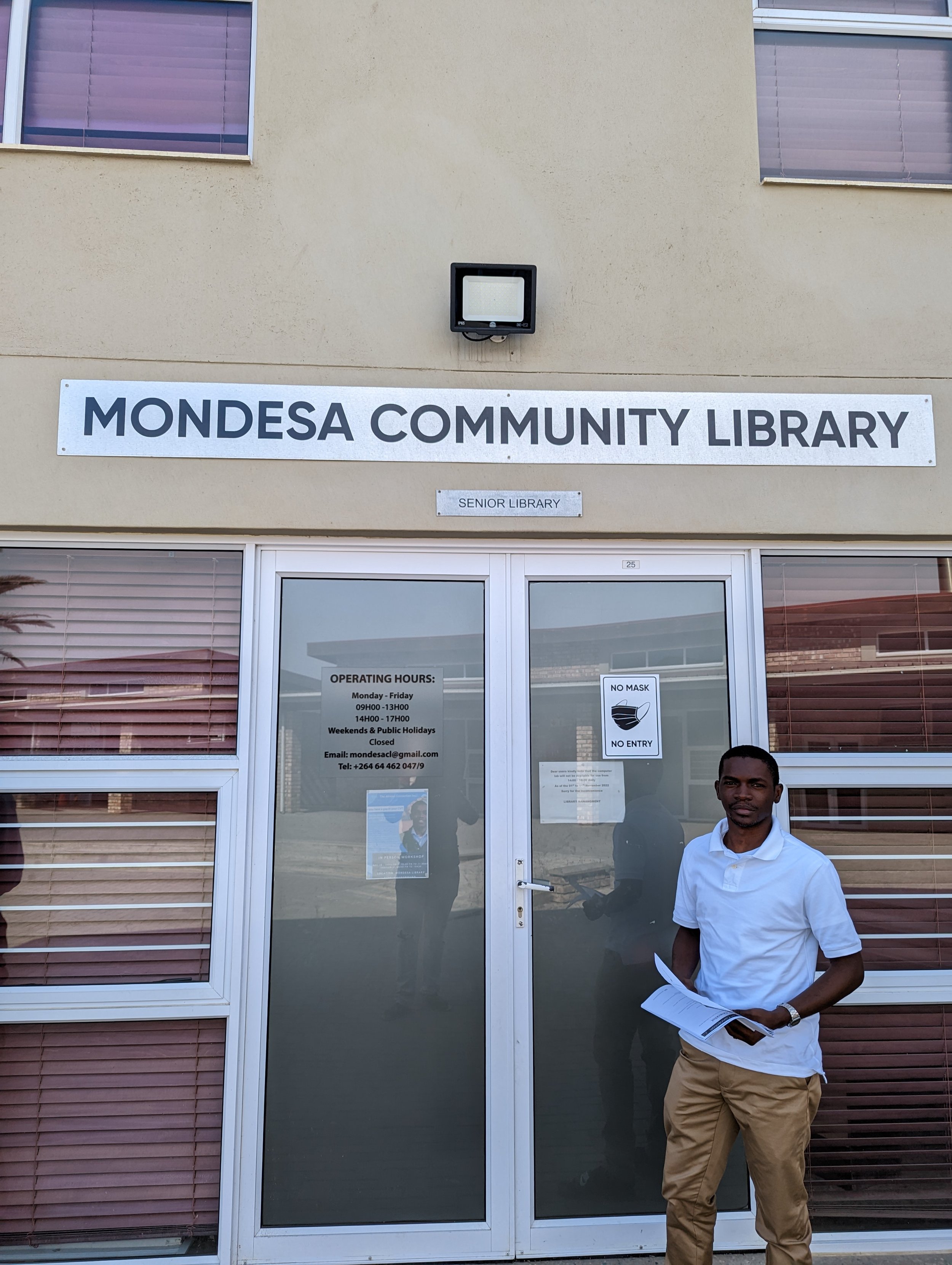 Mondesa Community Library entrance with a person holding documents standing nearby.