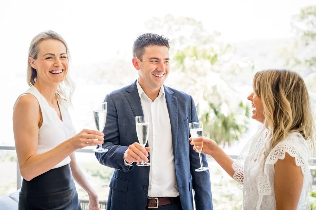 Three Specialist Broking team members smiling and raising champagne glasses together, celebrating the start of the year.