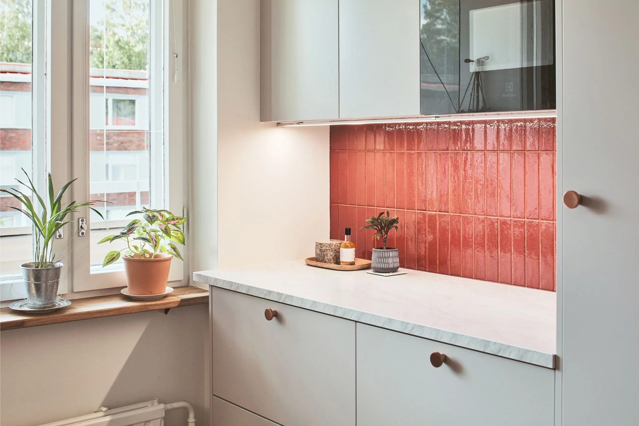 Marmorikuvioinen taso ja punainen tiililaatoitus keittiössä